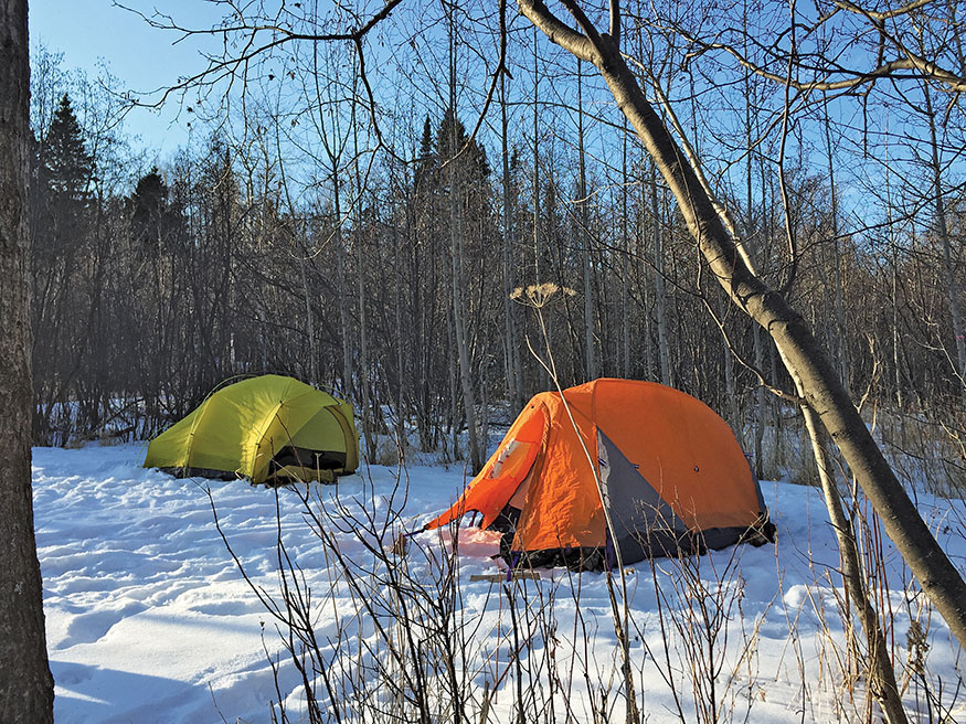 two tents in the woods with snow on the ground